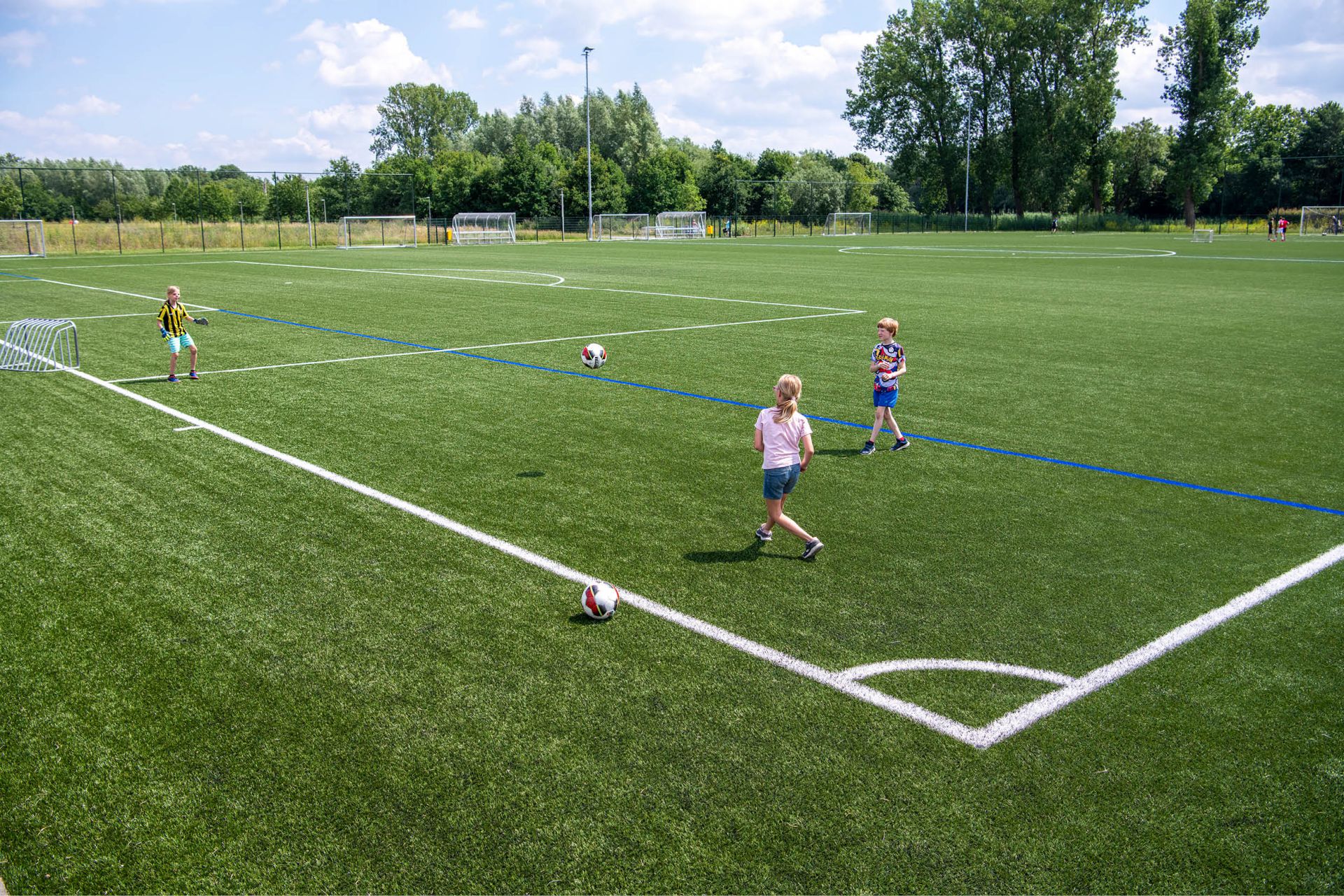 Voetbalveld met voetballende kinderen