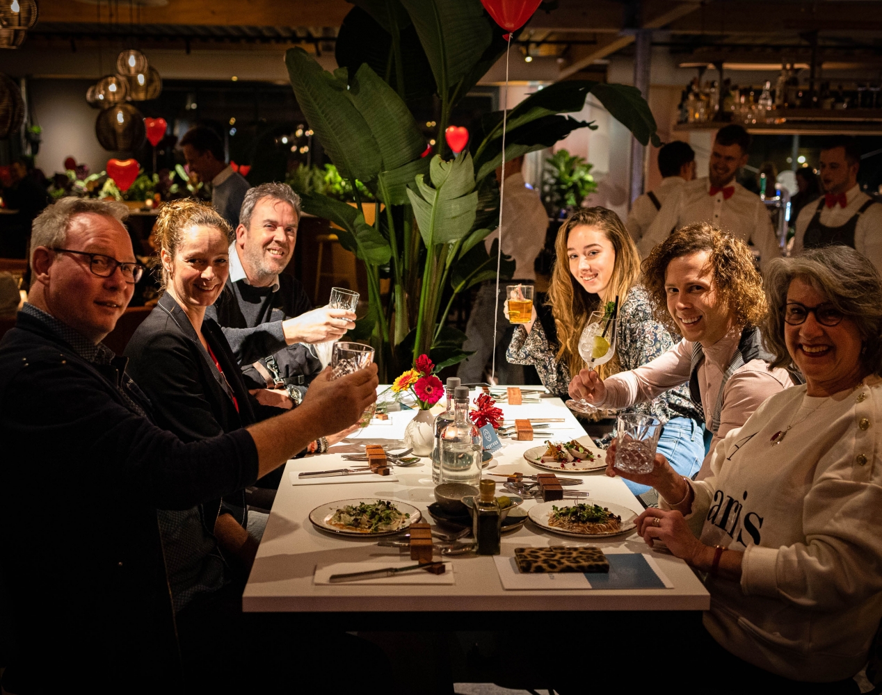 Tafel met dinerende en proostende mensen in een restaurant